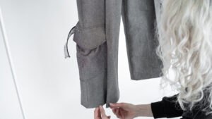 Das Hosenbein einer Jeans mit aufgenähten Taschen und einer Person, die den Saum zurecht rückt.