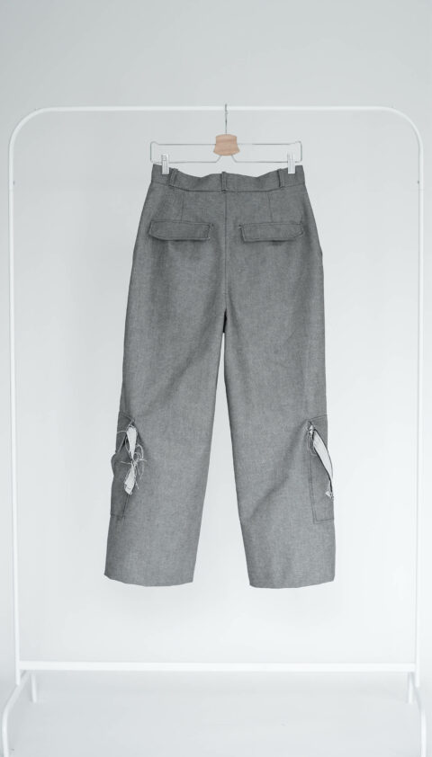 Rückenansicht einer Jeans mit aufgenähten Taschen, die an einem Kleiderständer hängt