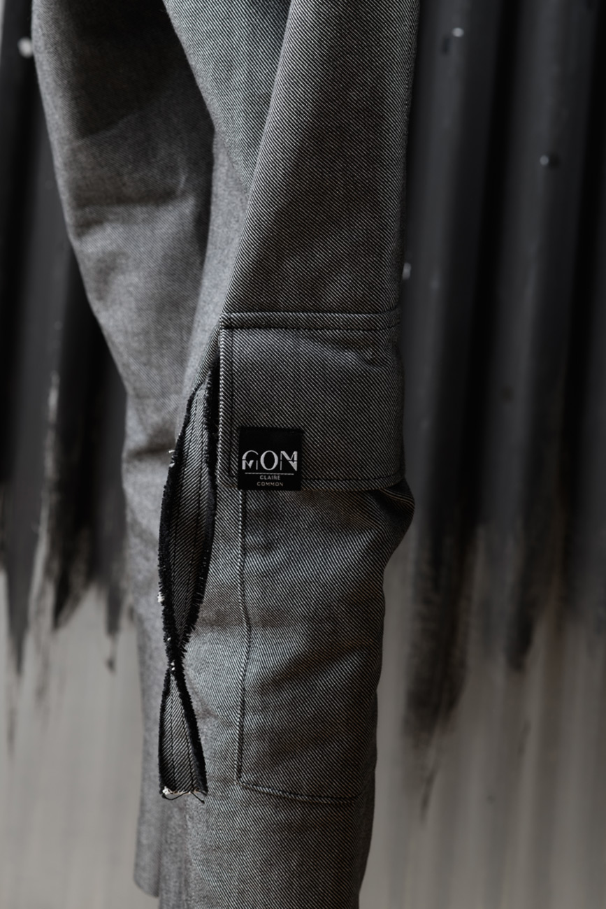 Ein Detailfoto des rechten Beines einer Jeanshose. Im Mittelpunkt steht eine aufgenähte Tasche mit Band und einem Etikett mit Logo.